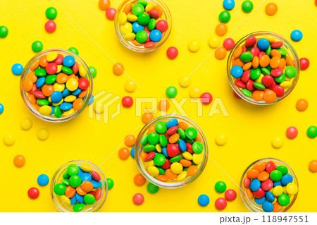 different colored round candy in bowl and jars. Top view of large variety sweets and candies with copy space different colored round candy in bowl and jars. Top view of large variety sweets and candies with copy space 118947551