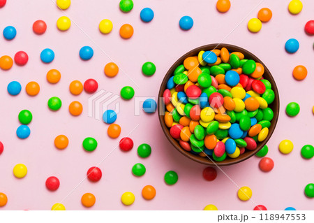 Multicolored candies in a bowl on a colored background. birthday and holiday concept. Top view with copy space 118947553