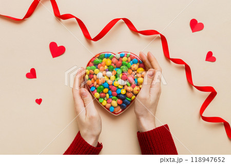 Female hands with delicious candies in box on color background 118947652
