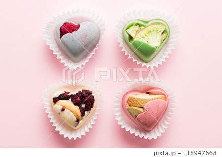 chocolate sweets in the form of a heart with fruits and nuts on a colored background. top view with space for text, holiday concept 118947668