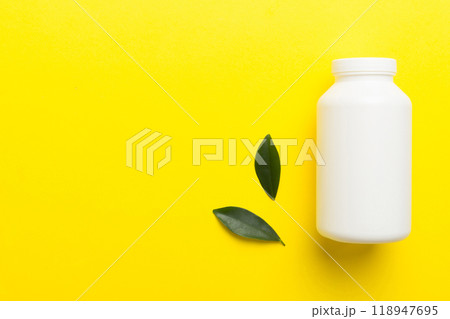supplement pills with medicine bottle health care and medical top view. Vitamin tablets. Top view mockup bottle for pills and vitamins with green leaves, natural organic bio supplement, copy space 118947695