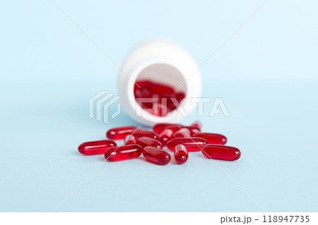 Red pills spilled around a pill bottle. Medicines and prescription pills flat lay background. Red medical capsules Red pills spilled around a pill bottle. Medicines and prescription pills flat lay background. Red medical capsules 118947735