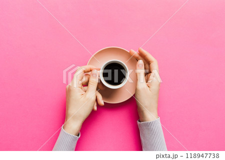 Minimalistic style woman hand holding a cup of coffee on Colored background. Flat lay, top view cappuccino cup. Empty place for text, copy space. Coffee addiction. Top view, flat lay 118947738