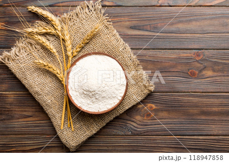 Flat lay of Wheat flour in wooden bowl with wheat spikelets on colored background. world wheat crisis 118947858