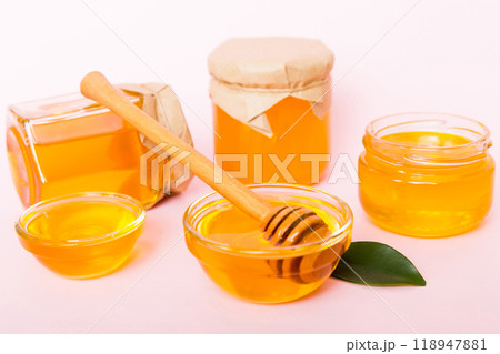 Honey in jar with leaves and honey dipper on colored background top view with copy text 118947881