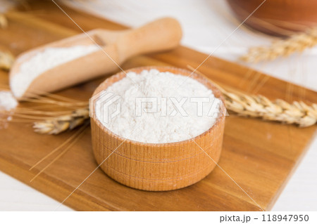Flat lay of Wheat flour in wooden bowl with wheat spikelets on colored background. world wheat crisis 118947950