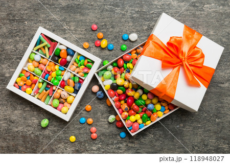 Set of different sweet candy in a paper box with a satin ribbon on a colored background. Holiday concept 118948027