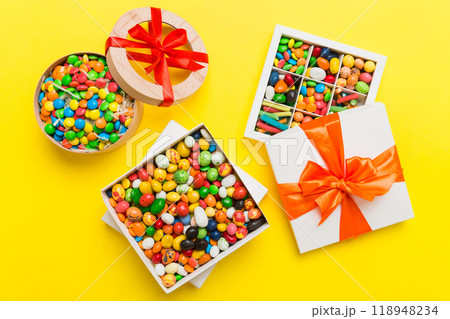 Set of different sweet candy in a paper box with a satin ribbon on a colored background. Holiday concept 118948234
