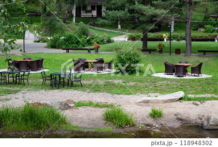 Outdoor seating area with wicker and metal furniture on lush green lawn. 118948302
