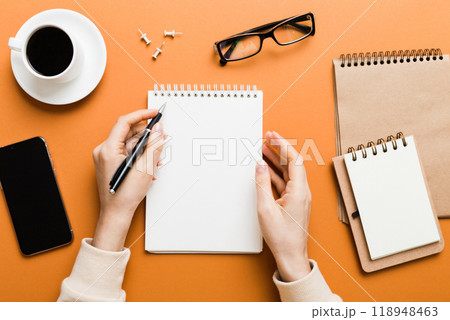 Woman hand with pencil writing on notebook and hold coffee cup. Woman working on office table with coffee 118948463