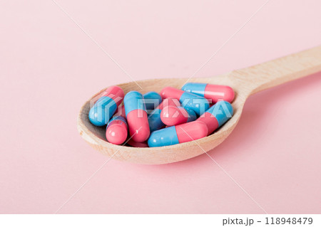 Vitamin capsules in a spoon on a colored background. Pills served as a healthy meal. Red soft gel vitamin supplement capsules on spoon Vitamin capsules in a spoon on a colored background. Pills served as a healthy meal. Red soft gel vitamin supplement capsules on spoon 118948479