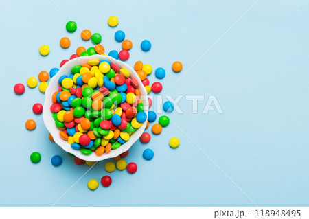 Multicolored candies in a bowl on a colored background. birthday and holiday concept. Top view with copy space 118948495