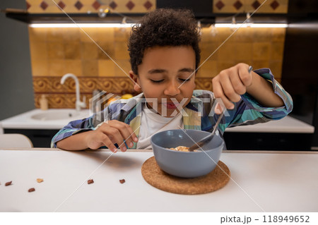 Dark-skinned boy sitting at the table and eating breakfast 118949652