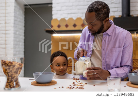 Dad offering some milk to his son during breakfast Dad offering some milk to his son during breakfast 118949682