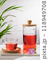 Red fruit infusion in crystal glass and pitcher on wooden base. Vertical format. 118949708