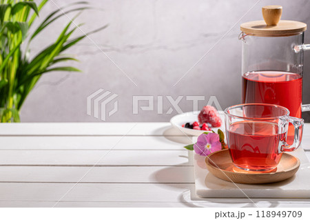 Red fruit infusion in crystal glass and pitcher on wooden base with copy space. 118949709