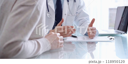 Doctor consulting patient. Male physician is using a clipboard while talking with a woman in a clinic, close up. Medicine concept Doctor consulting patient. Male physician is using a clipboard while talking with a woman in a clinic, close up. Medicine concept 118950120