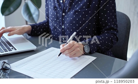 Businesswoman professional writing in a notebook beside a laptop at a modern workplace, close up view. Business concept Businesswoman professional writing in a notebook beside a laptop at a modern workplace, close up view. Business concept 118950203