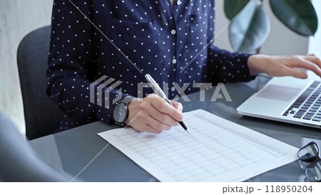 Businesswoman professional writing in a notebook beside a laptop at a modern workplace, close up view. Business concept Businesswoman professional writing in a notebook beside a laptop at a modern workplace, close up view. Business concept 118950204