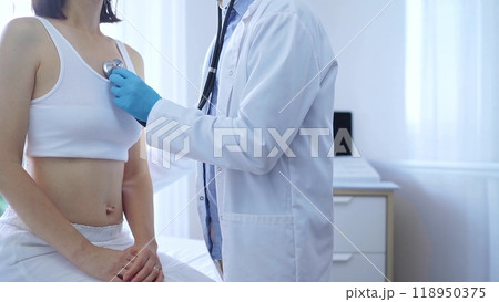 Doctor and patient. Physician wearing blue medical gloves is using stethoscope examining woman lungs in clinic. Medicine concept Doctor and patient. Physician wearing blue medical gloves is using stethoscope examining woman lungs in clinic. Medicine concept 118950375