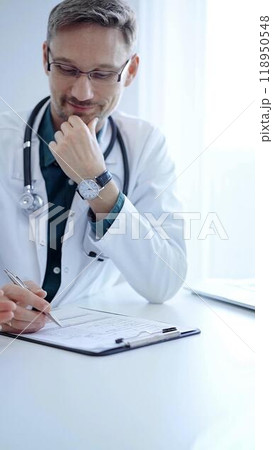 Doctor and a patient. The physician, wearing a white medical coat over a green shirt, gesturing with his hands during a consultation in the clinic. Medicine concept Doctor and a patient. The physician, wearing a white medical coat over a green shirt, gesturing with his hands during a consultation in the clinic. Medicine concept 118950548