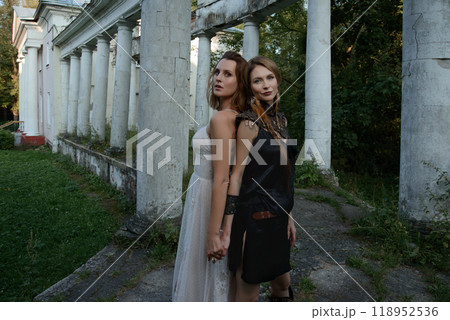 Two beautiful girls, sisters Lilith and Eva, pose in rocking dresses against the background of columns. 118952536