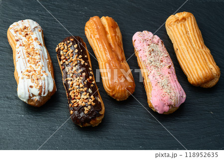 Assorted eclairs on a pastel top view Traditional French dessert 118952635