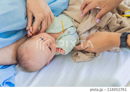 A nurse is taking a baby's temperature in the hospital. The gentle and careful procedure ensures the baby's comfort and well-being, allowing for accurate monitoring of their health 118952761