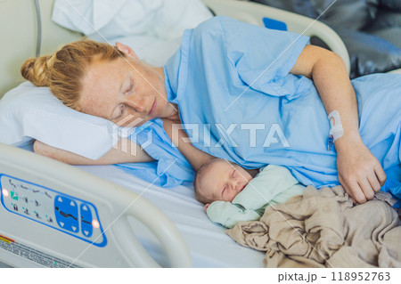 A baby lies with the mother after childbirth, resting peacefully. The serene moment captures the bond between mother and child as they begin their journey together. The hospital environment ensures a 118952763