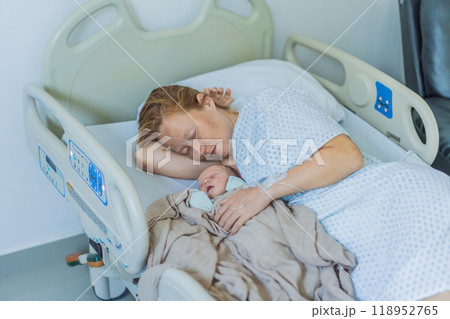 A baby lies with the mother after childbirth, resting peacefully. The serene moment captures the bond between mother and child as they begin their journey together. The hospital environment ensures a 118952765