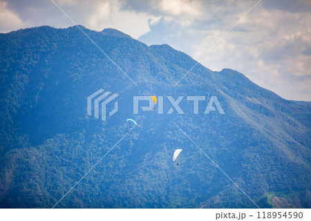 People paragliding over the beautiful mountains of the Antioquia department in Colombia. Tandem Paragliding. Extreme sport concept. People paragliding over the beautiful mountains of the Antioquia department in Colombia. Tandem Paragliding. Extreme sport concept. 118954590