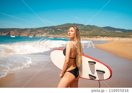 Sensuous surfer girl in bikini carrying surfboard Sensuous surfer girl in bikini carrying surfboard 118955816