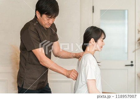 整体院・整骨院・マッサージに通う女性と整体師・セラピスト 118957007