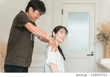 整体院・整骨院・マッサージに通う女性と整体師・セラピスト 整体院・整骨院・マッサージに通う女性と整体師・セラピスト 118957413