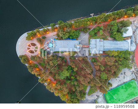 A top down, aerial view of the evening city park on the river bank. A top down, aerial view of the evening city park on the river bank. 118959508