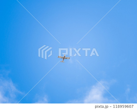 Small ultralight airplane with overhead wing and single propeller flying in sunset sky. 118959607