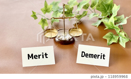 天秤と2枚のカードにMeritとDemerit文字_茶色背景 118959968