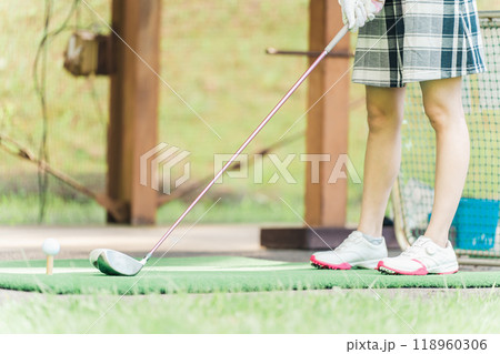 ゴルフ練習場でドライバーを構える女性ゴルファーの足元 118960306