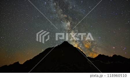 A mountain silhouette stands beneath a star-speckled sky, with the Milky Way arching above. 118960510