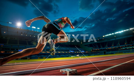 A sprinter bursts from the blocks, feet off the ground, stadium lights highlighting their determination. 118960594