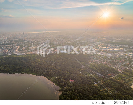Big lake with green shores in bright sun light and city on horizon, aerial landscape. Recreation concept. Aerial view 118962366