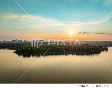 Big lake with green shores in bright sun light and city on horizon, aerial landscape. Recreation concept. Aerial view Big lake with green shores in bright sun light and city on horizon, aerial landscape. Recreation concept. Aerial view 118962368