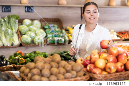 Young woman choosing ripe apples on produce display in store Young woman choosing ripe apples on produce display in store 118963135