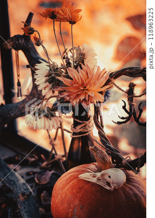 Atmospheric home autumn altar. Dry birds claws and skull, pumpkin, willow wreath, beautiful flowers and branches on wooden surface, vertical format. Atmospheric home autumn altar. Dry birds claws and skull, pumpkin, willow wreath, beautiful flowers and branches on wooden surface, vertical format. 118963225