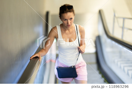 Woman coming out of metro station, moving up on escalator Woman coming out of metro station, moving up on escalator 118963296