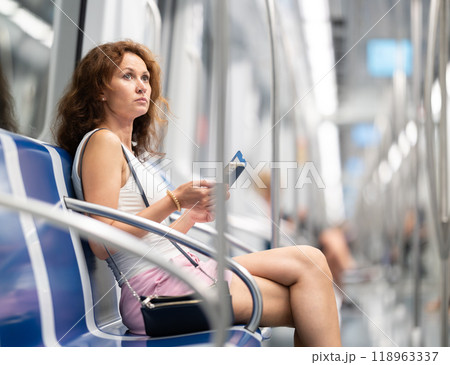 Portrait of a woman holding a smartphone in subway car 118963337