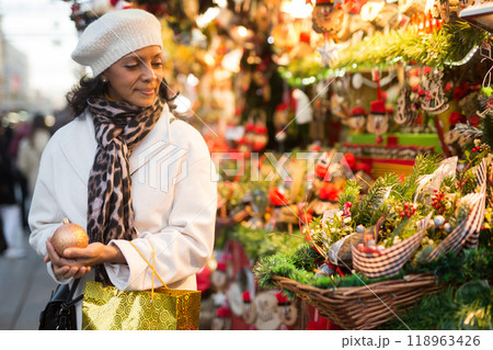 Latin American woman chooses Christmas souvenirs and toys Latin American woman chooses Christmas souvenirs and toys 118963426