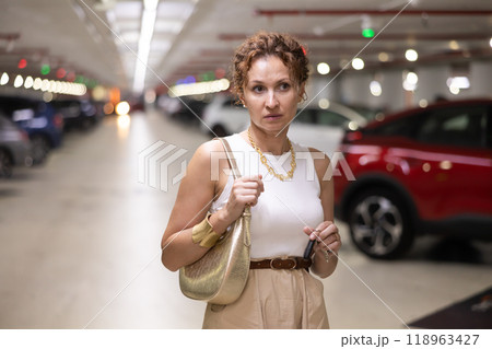 Adult woman stands in parking lot with keys 118963427