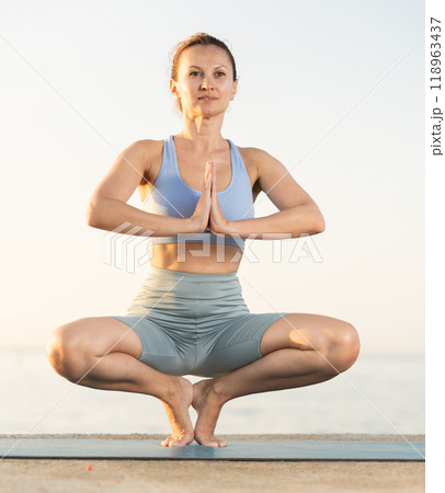 Near sea during sunset, girl performs prapadasana 118963437