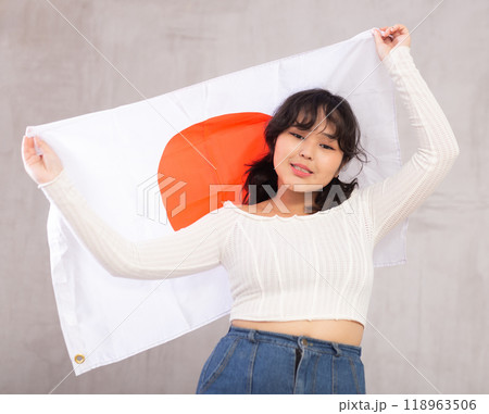 Displeased young girl holding Japan flag Displeased young girl holding Japan flag 118963506